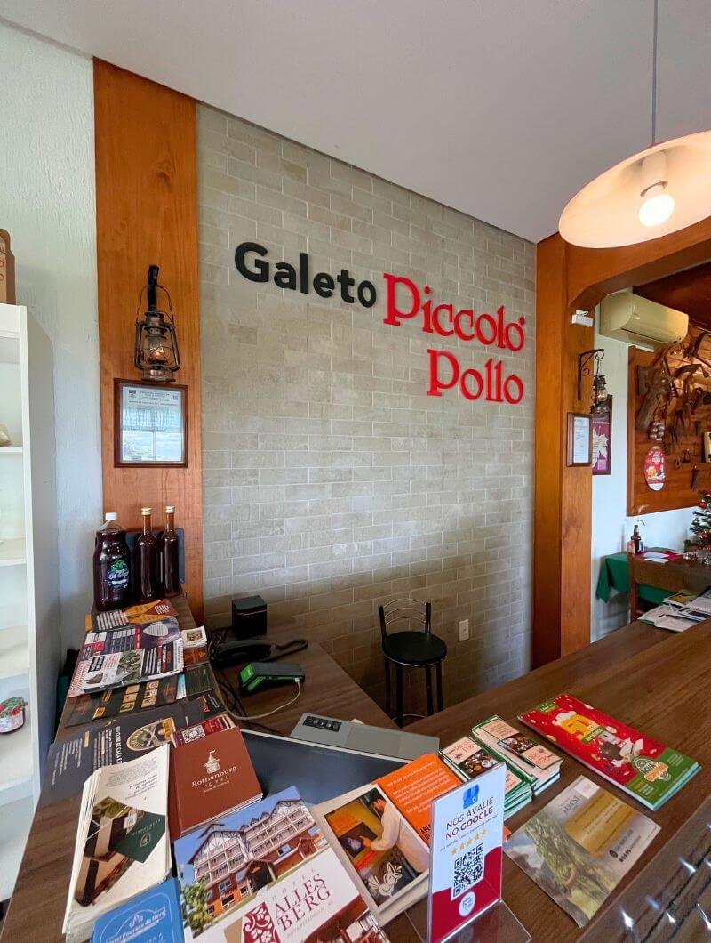 Recepção com logo do Galeto Piccolo Pollo em Nova Petrópolis, destaque para produtos e lembranças da casa.